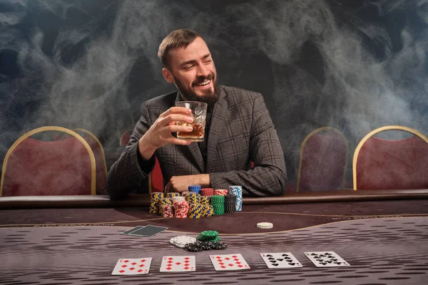 Όμορφος γενειοφόρος άνδρας παίζει πόκερ κάθεται στο τραπέζι στο καζίνο. — Φωτογραφία Αρχείου