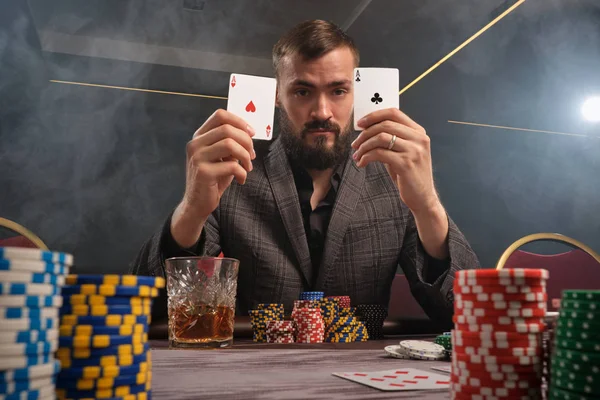 Красивый бородатый мужчина играет в покер, сидя за столом в казино . — стоковое фото
