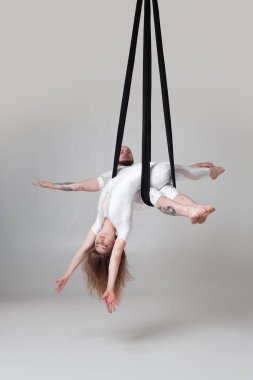 Güzel kız ve beyaz spor takım elbiseli bir atletik adam bir stüdyoda bir akrobatik unsurlar gerçekleştiriyor.