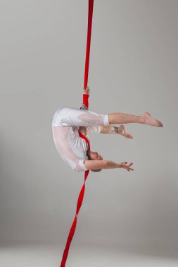 Beyaz spor takım elbiseli atletik adam bir stüdyoda bir akrobatik unsurlar yapıyor.