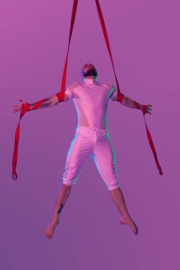 Beyaz spor takım elbiseli atletik adam bir stüdyoda bir akrobatik unsurlar yapıyor.