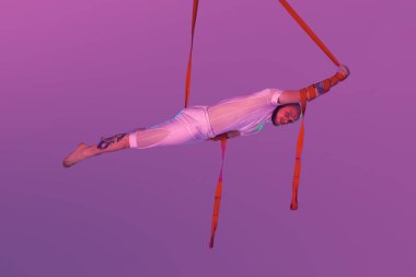 Beyaz spor takım elbiseli atletik adam bir stüdyoda bir akrobatik unsurlar yapıyor.