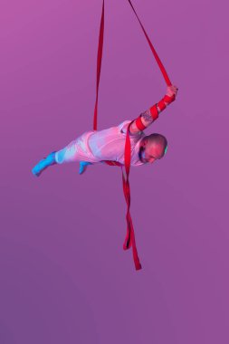 Beyaz spor takım elbiseli atletik adam bir stüdyoda bir akrobatik unsurlar yapıyor.