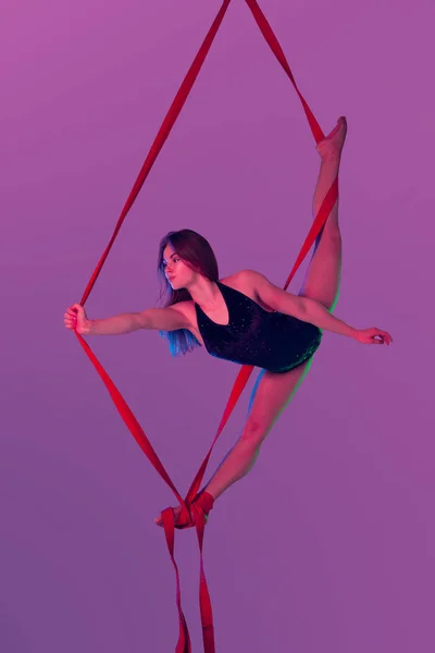 Beautiful girl in a black swimsuit is performing an acrobatic elements in studio. — Stock Photo, Image