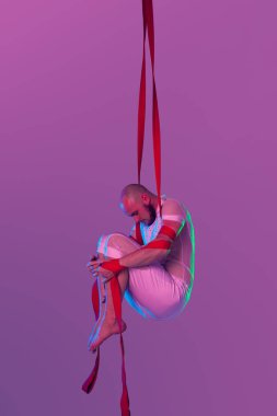 Beyaz spor takım elbiseli atletik adam bir stüdyoda bir akrobatik unsurlar yapıyor.