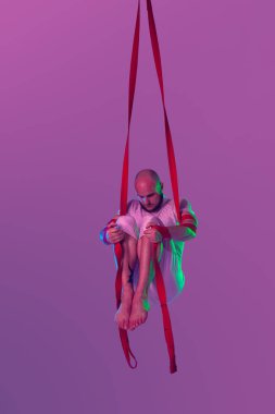 Beyaz spor takım elbiseli atletik adam bir stüdyoda bir akrobatik unsurlar yapıyor.