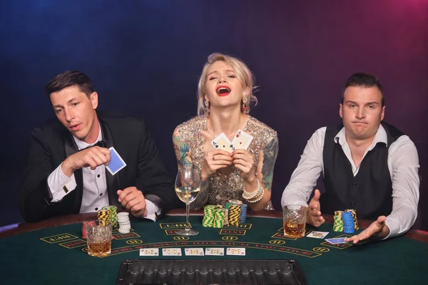 Group of a young wealthy friends are playing poker at a casino.