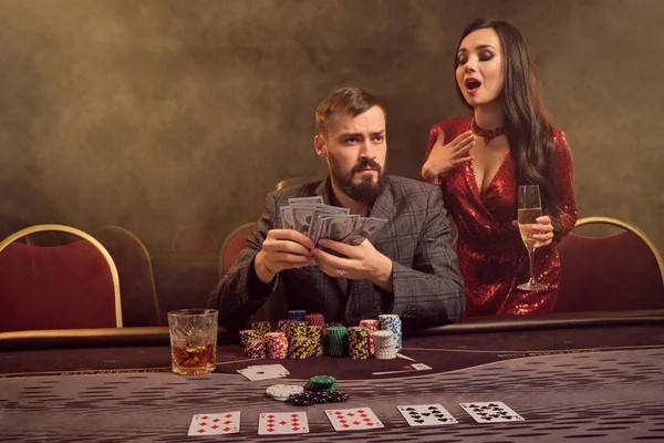 Encantadora pareja rica está jugando al póquer en un casino . — Foto de Stock