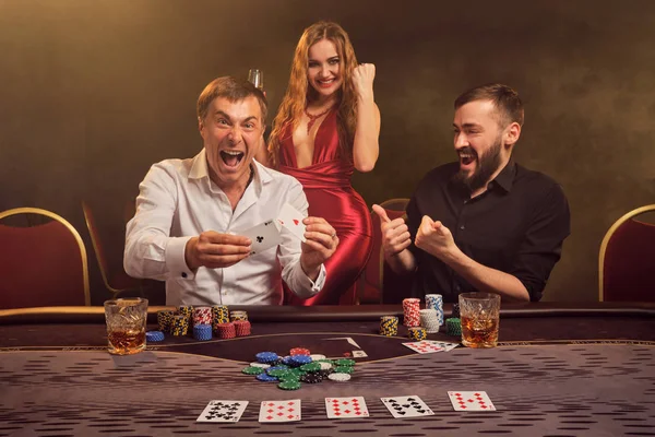 Grupo de jóvenes amigos ricos están jugando al póquer en un casino . — Foto de Stock