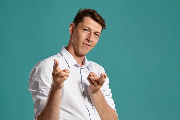 Jongeman in een klassiek wit shirt poseert over een blauwe achtergrond. — Stockfoto