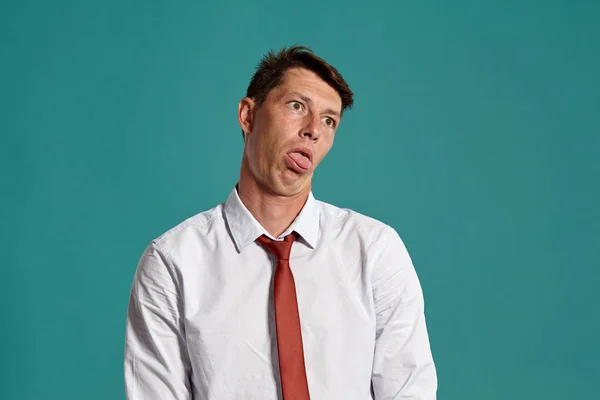 Hombre joven con una camisa blanca clásica y corbata roja posando sobre un fondo azul . — Foto de Stock