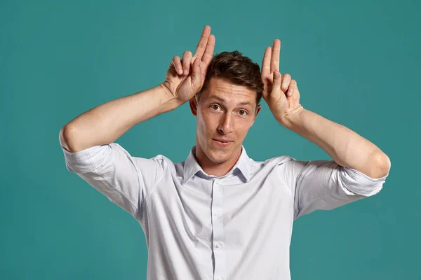 Jongeman in een klassiek wit shirt poseert over een blauwe achtergrond. — Stockfoto