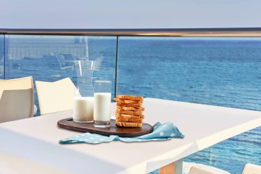 İki kişilik masa, açık hava otel balkonunda deniz manzaralı bir kahvaltıyla servis edilecek..