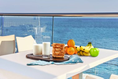 İki kişilik masa, açık hava otel balkonunda deniz manzaralı bir kahvaltıyla servis edilecek..