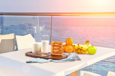 İki kişilik masa, açık hava otel balkonunda deniz manzaralı bir kahvaltıyla servis edilecek..