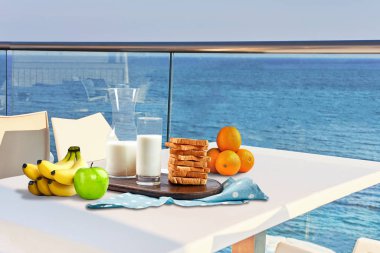 İki kişilik masa, açık hava otel balkonunda deniz manzaralı bir kahvaltıyla servis edilecek..