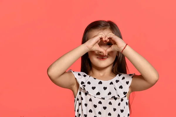 ピンクの背景に対してポーズ美しいブルネットの小さな女の子のクローズアップスタジオショット. — ストック写真