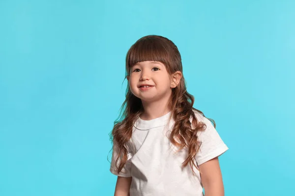 Gyönyörű kislány visel egy fehér póló pózol ellen kék stúdió háttérben. — Stock Fotó