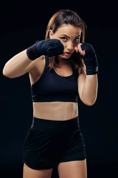 Mujer atlética en guantes de boxeo está practicando karate en estudio . —  Fotos de Stock