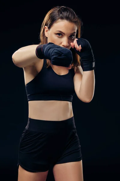 Athletic woman in boxing mittens is practicing karate in studio.