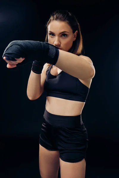 Mujer atlética en guantes de boxeo está practicando karate en estudio . — Foto de Stock