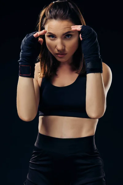Athletic woman in boxing mittens is practicing karate in studio.