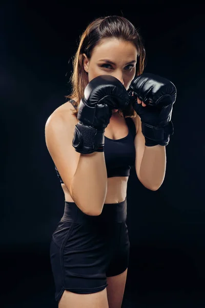 Спортивная женщина в боксёрских перчатках занимается карате в студии . — стоковое фото