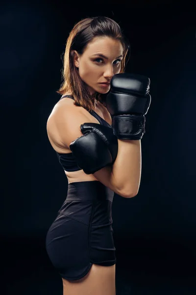 Mulher atlética em luvas de boxe está praticando karatê em estúdio . — Fotografia de Stock