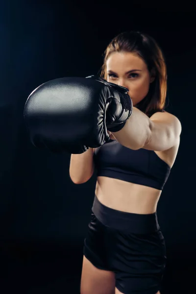 Mujer atlética en guantes de boxeo está practicando karate en estudio . — Foto de Stock