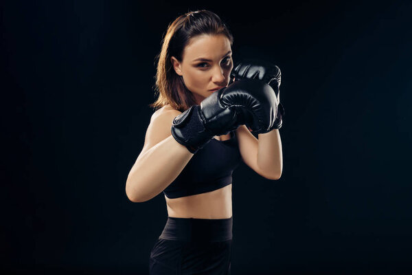 Athletic woman in boxing gloves is practicing karate in studio.