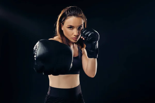 Mulher atlética em luvas de boxe está praticando karatê em estúdio . — Fotografia de Stock