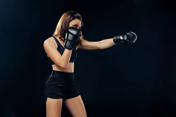Mujer atlética en guantes de boxeo está practicando karate en estudio . —  Fotos de Stock