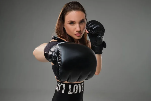 Mulher atlética em luvas de boxe está praticando karatê em estúdio . — Fotografia de Stock