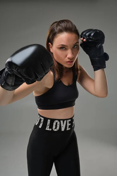 Mulher atlética em luvas de boxe está praticando karatê em estúdio . — Fotografia de Stock