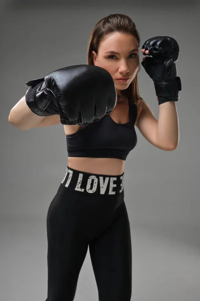 Mulher atlética em luvas de boxe está praticando karatê em estúdio . — Fotografia de Stock