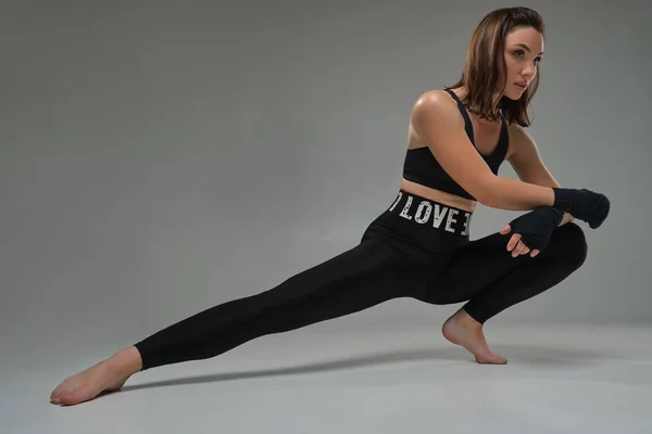 Athletic woman in boxing mittens is practicing karate in studio.