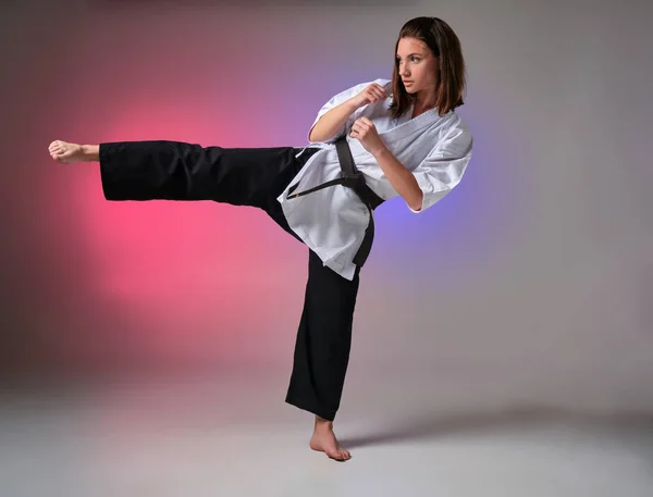 Donna atletica in kimono tradizionale sta praticando karate in studio . — Foto Stock
