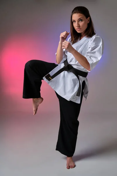 Athletic woman in traditional kimono is practicing karate in studio. — Stock Photo, Image