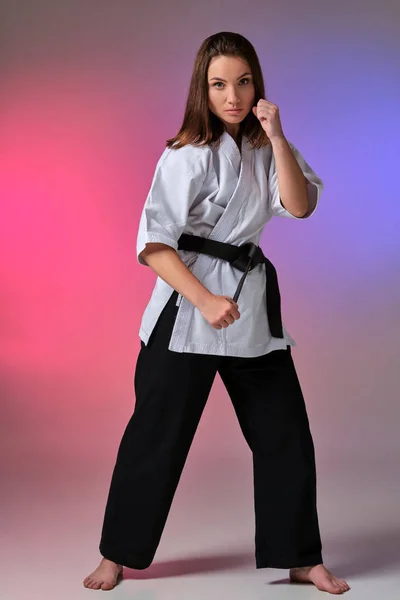 Mujer atlética en kimono tradicional está practicando karate en estudio . —  Fotos de Stock