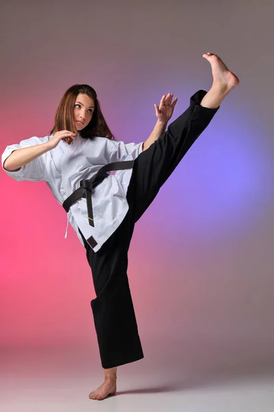 Αθλητική γυναίκα στο παραδοσιακό κιμονό είναι εξάσκηση καράτε στο στούντιο. — Φωτογραφία Αρχείου