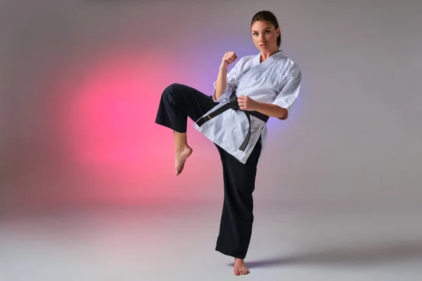 Mujer atlética en kimono tradicional está practicando karate en estudio . —  Fotos de Stock