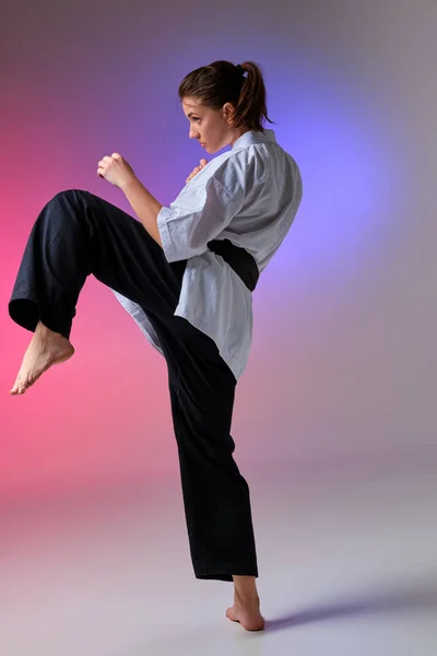 Donna atletica in kimono tradizionale sta praticando karate in studio . — Foto Stock