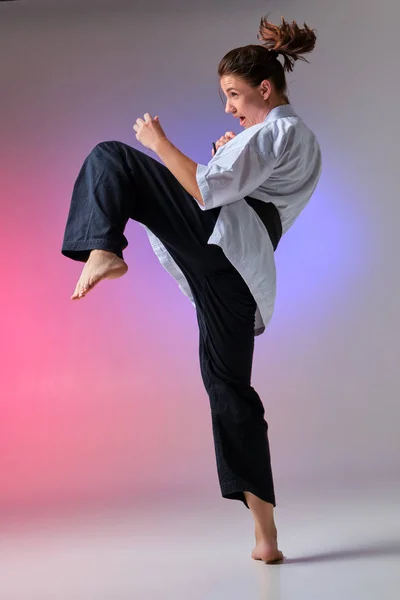 Mujer atlética en kimono tradicional está practicando karate en estudio . —  Fotos de Stock