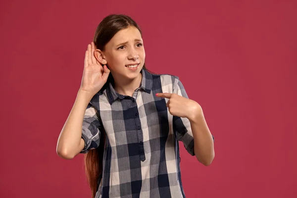 Schöne Teenager-Mädchen in einem lässig karierten Hemd posiert vor rosa Studiohintergrund. — Stockfoto