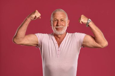 Yakışıklı olgun adam pembe bir stüdyo arka plan karşı poz.