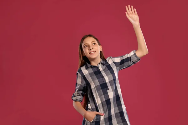 Mooie tiener meisje in een casual geruit shirt is poseren tegen een roze studio achtergrond. — Stockfoto