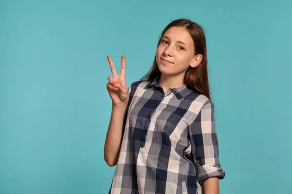 カジュアルなチェッカーシャツの美しい十代の少女は、青いスタジオの背景に対してポーズをとっています. — ストック写真