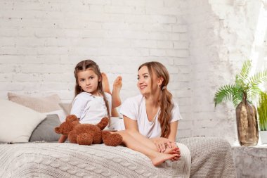 Yatak odası iç karşı poz onu sevimli küçük kızı ile güzel bir annenin Kapalı portre.