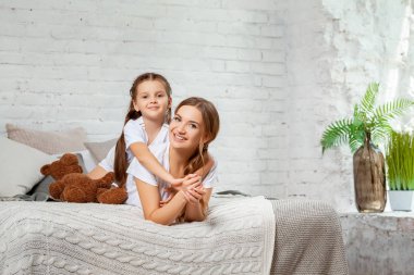 Yatak odası iç karşı poz onu sevimli küçük kızı ile güzel bir annenin Kapalı portre.