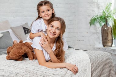 Yatak odası iç karşı poz onu sevimli küçük kızı ile güzel bir annenin Kapalı portre.